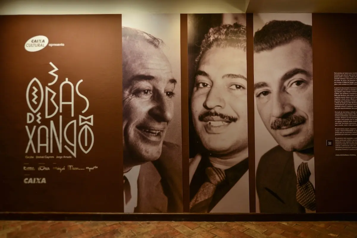 A exposição “3 Obás de Xangô” está em cartaz gratuitamente na CAIXA Cultural Salvador – Unidade Pelourinho até 06/12/2026. Inspirada no documentário de Sérgio Machado, a mostra reúne mais de 45 artistas e aborda as trajetórias de Jorge Amado, Carybé e Dorival Caymmi, além do Candomblé, da intelectualidade negra e das lideranças femininas. A programação ocupa imóvel histórico de 7.822,14 m² no Centro Histórico de Salvador.